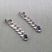 Close-up sapphire drop earrings with silver chain detail