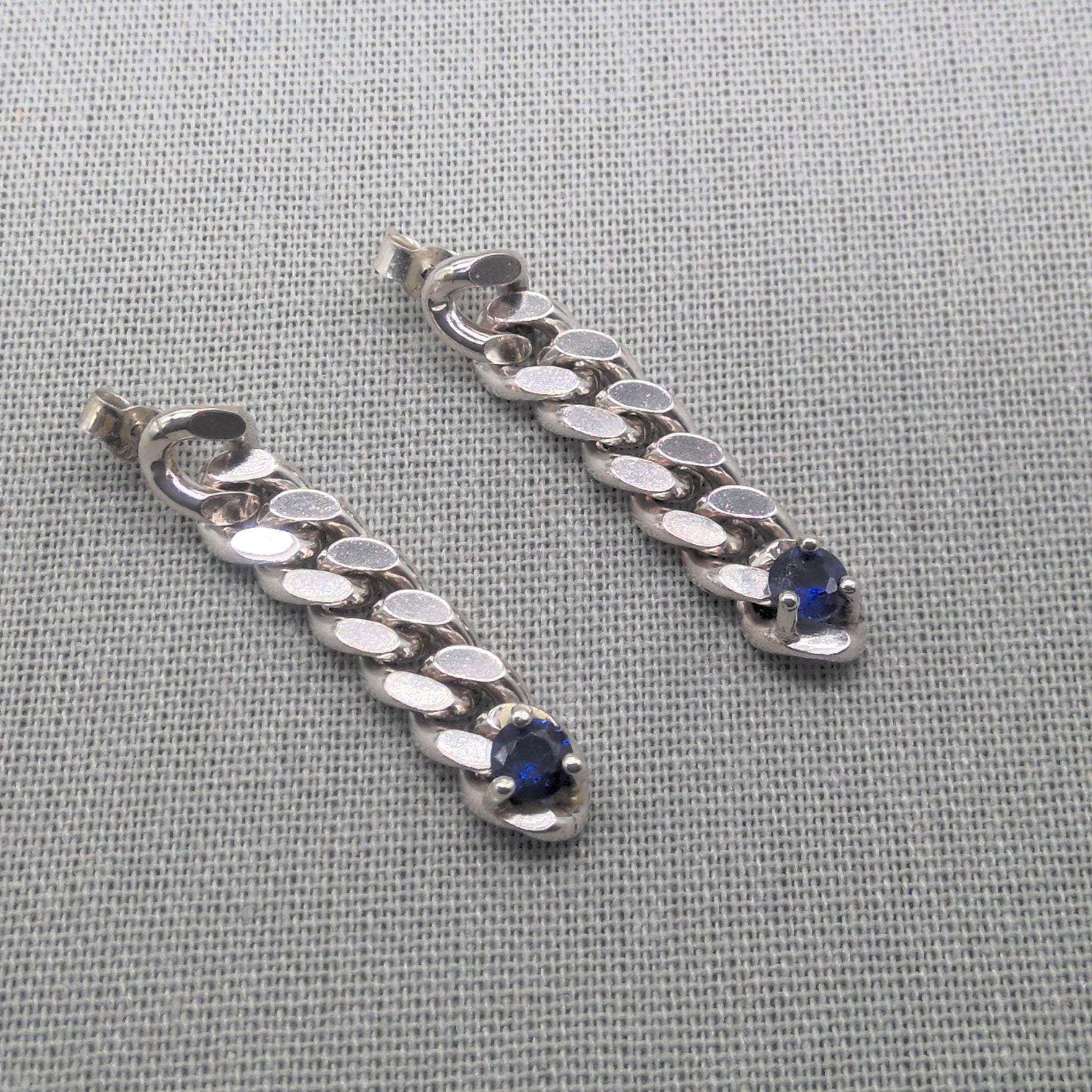 Close-up sapphire drop earrings with silver chain detail