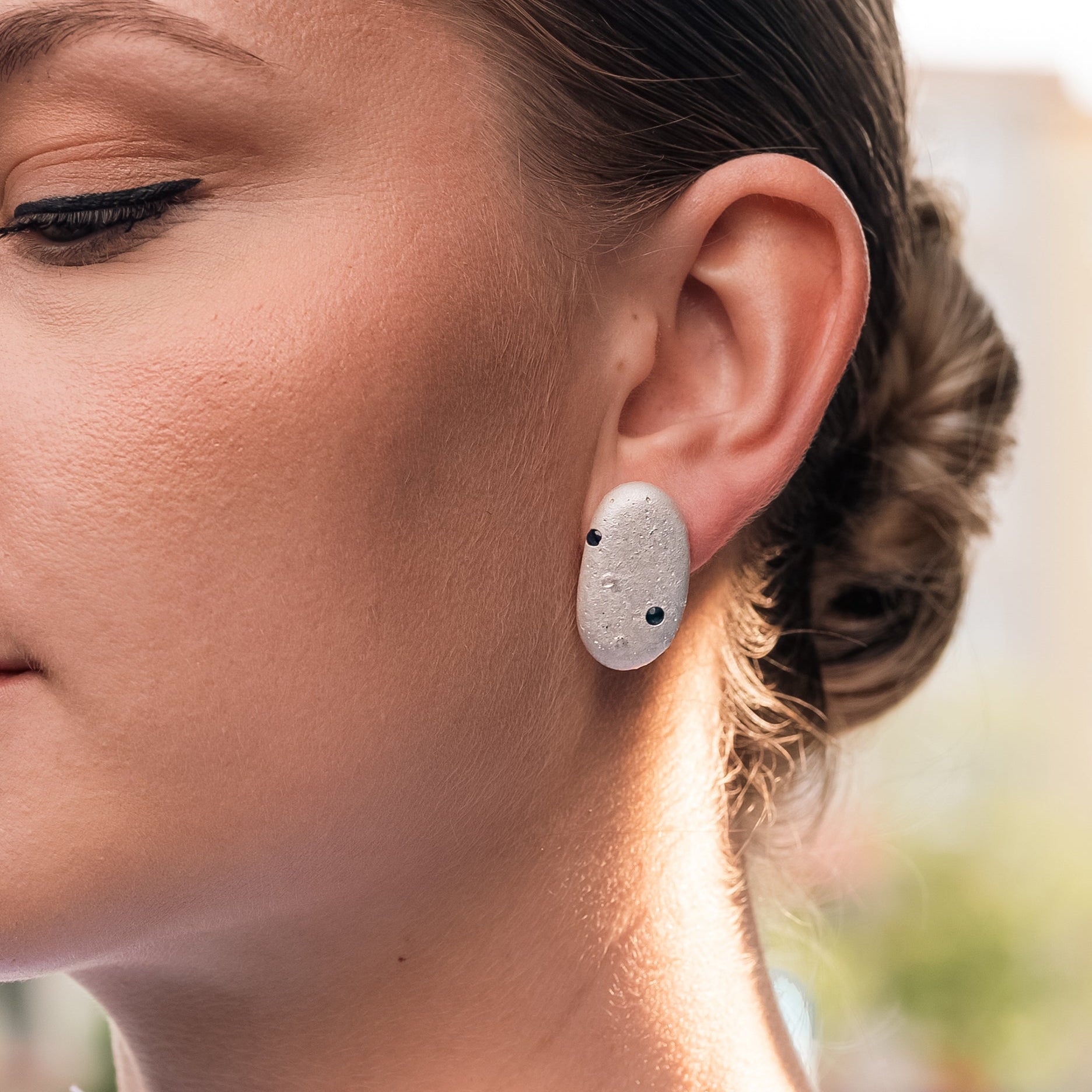 Woman wearing silver pebble earrings with sapphires, styled shot
