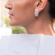 Silver pebble earring with sapphire worn on ear, side profile