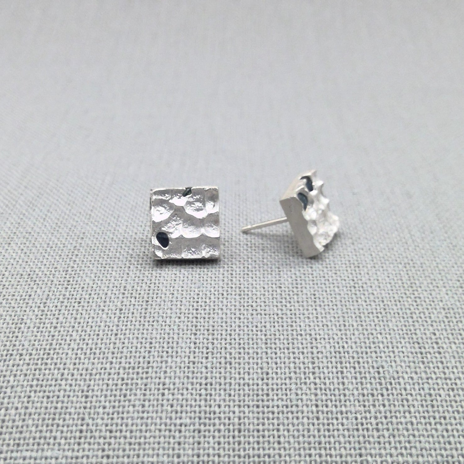 Textured silver earrings with blue sapphire stones, close-up