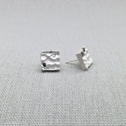 Textured silver earrings with blue sapphire stones, close-up