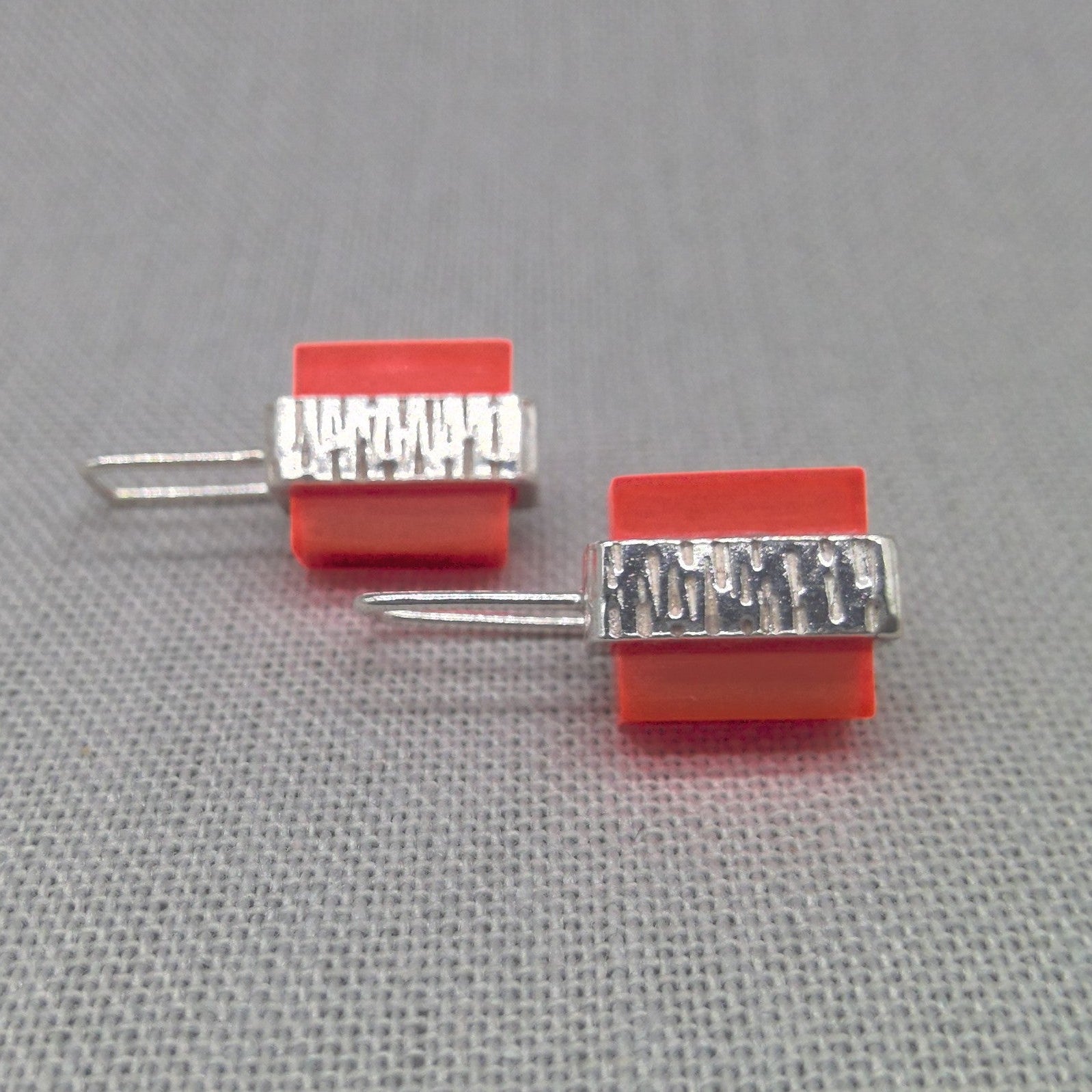 Close-up of orange Perspex block on textured silver stud