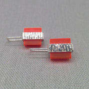 Close-up of orange Perspex block on textured silver stud