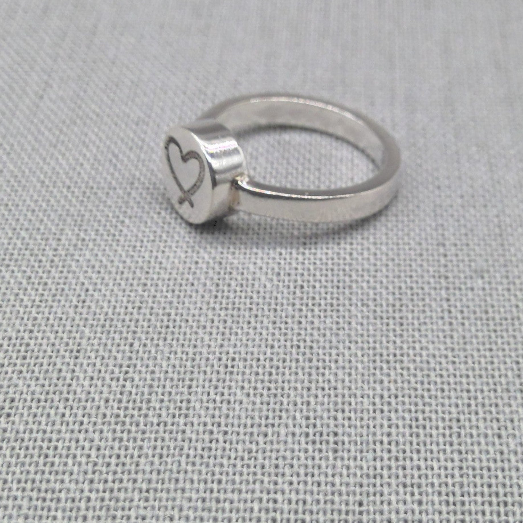 Personalised recycled silver ring with engraved heart disc on fabric