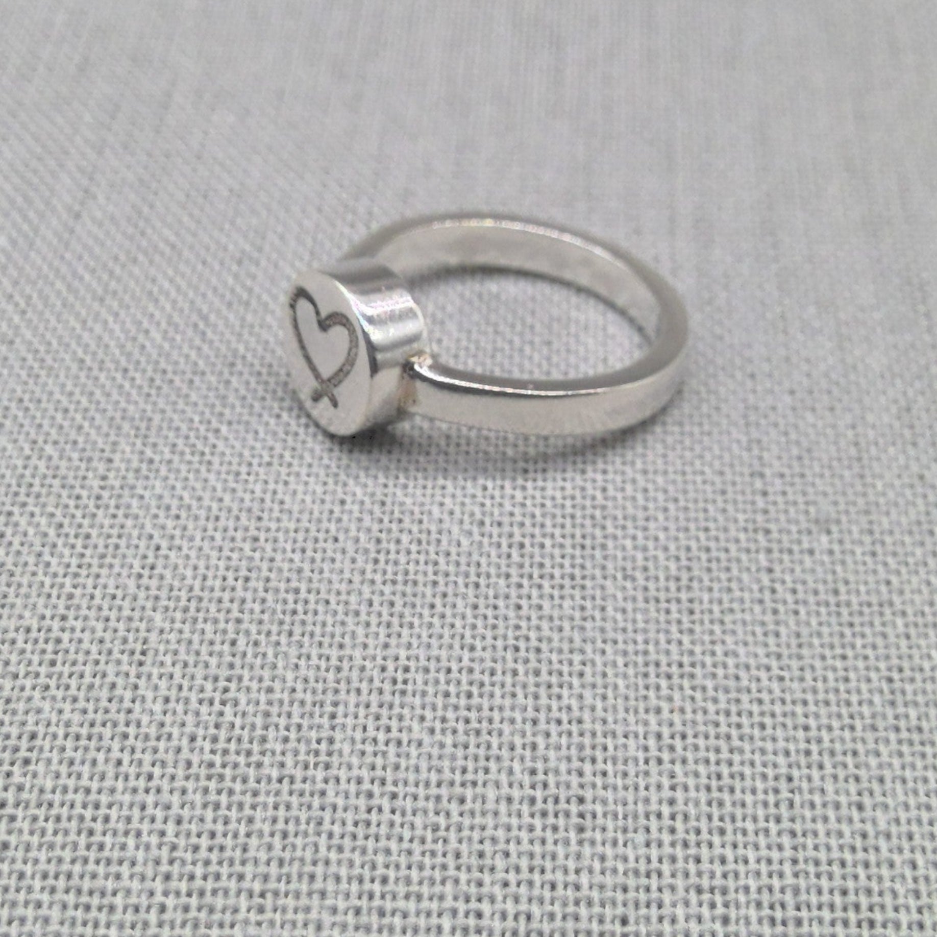 Angled view of personalised silver ring with heart engraving