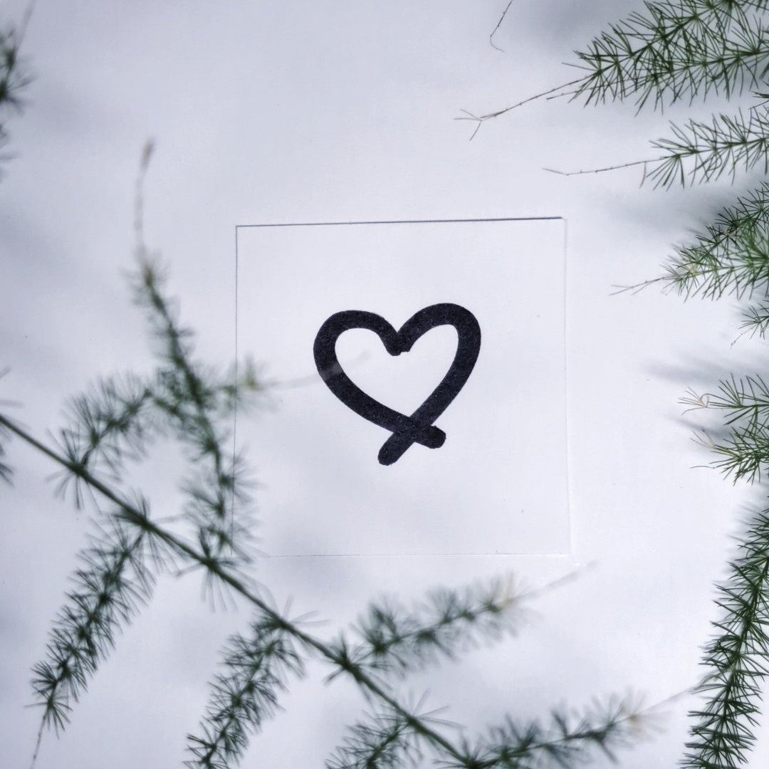 Heart symbol engraving detail shown outdoors against greenery