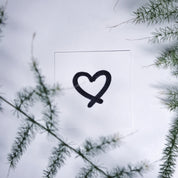 Heart symbol engraving detail shown outdoors against greenery