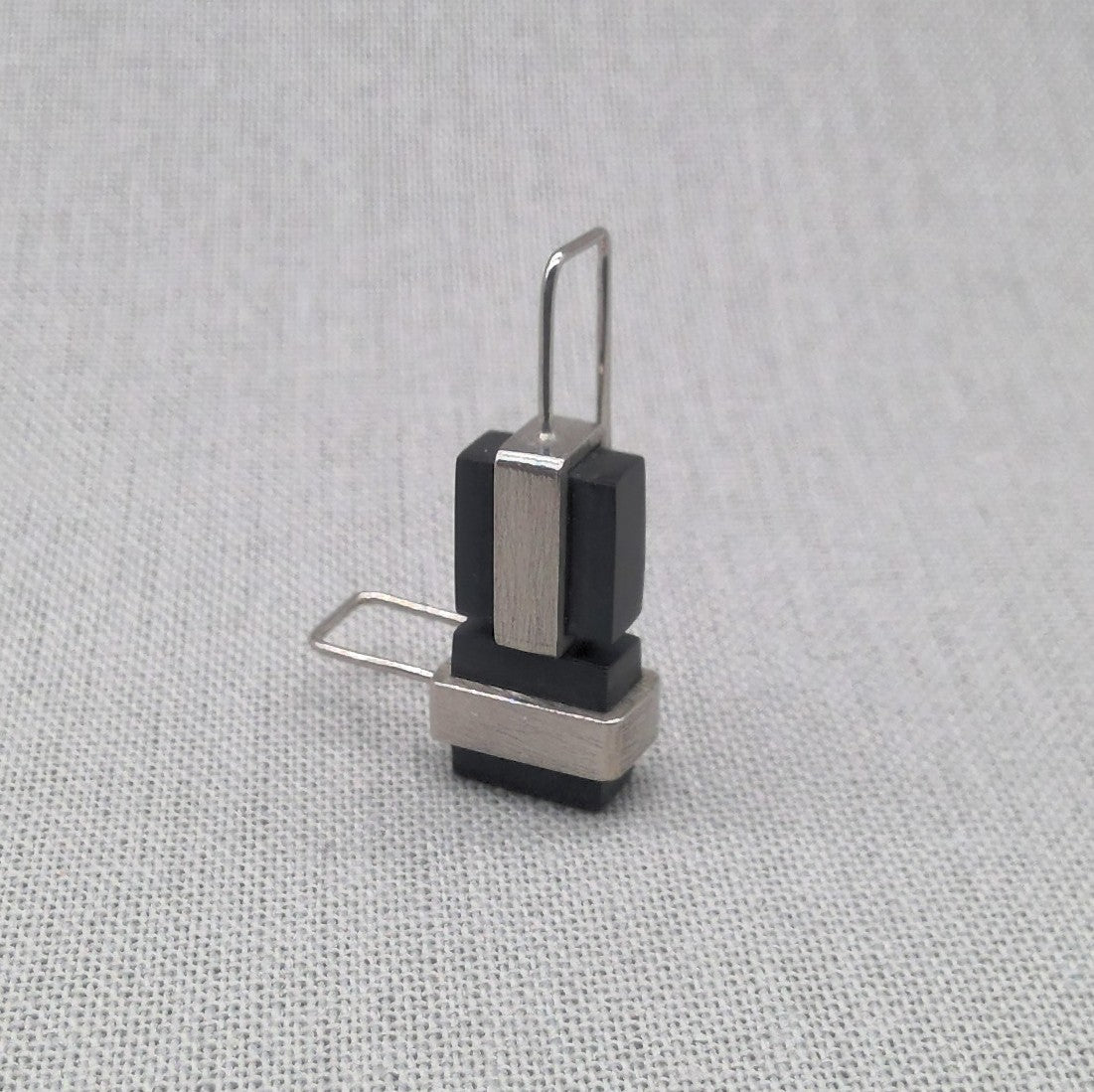 Angled view of black Perspex and silver drop earring