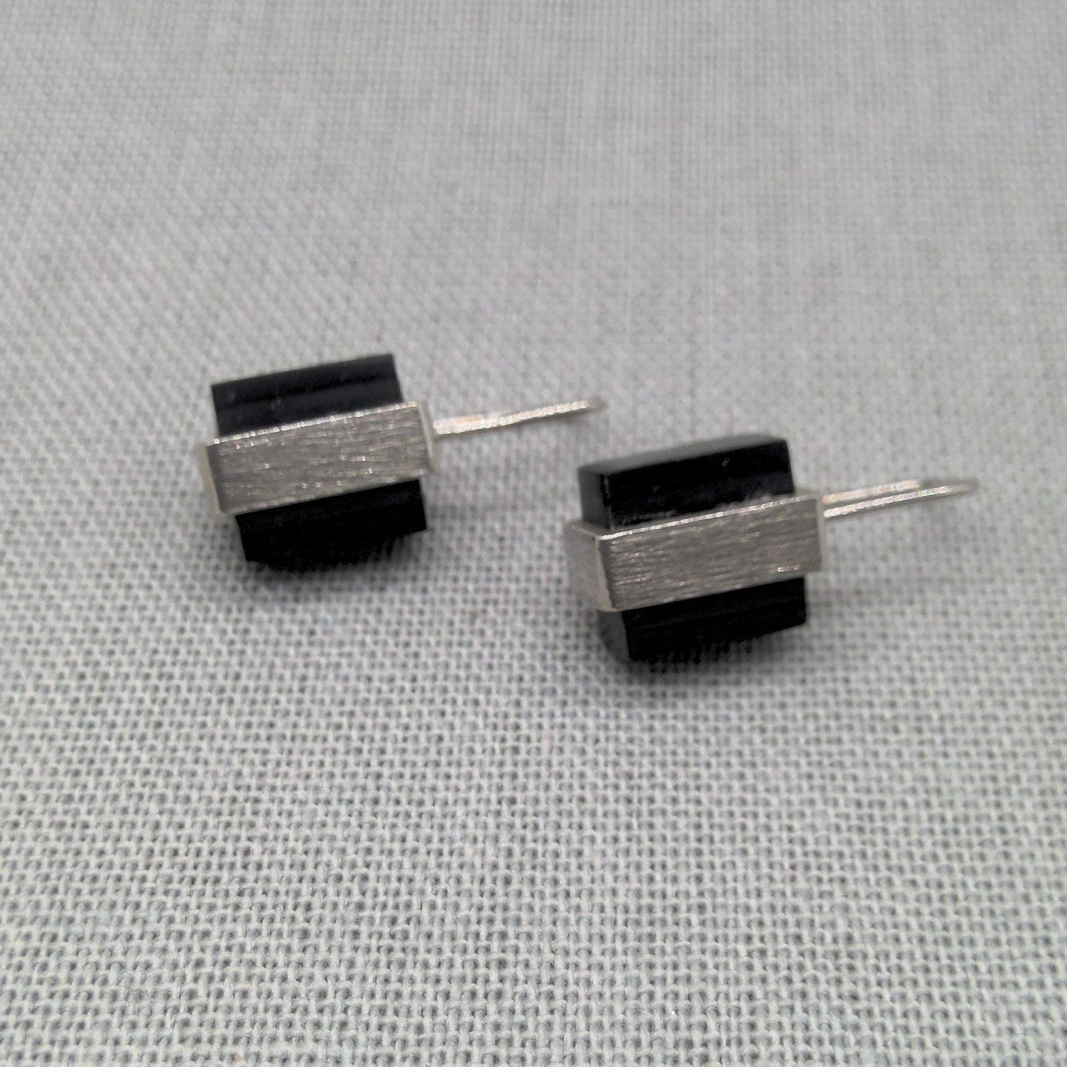 Flat lay of black Perspex and silver drop earrings