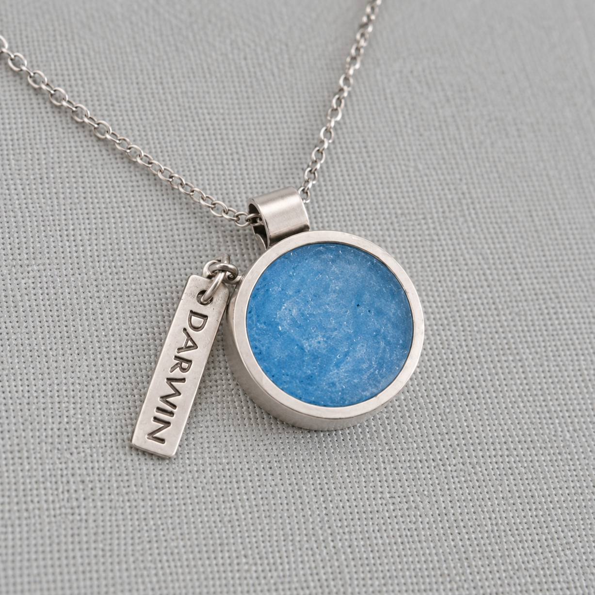 Recycled silver pet memorial ashes pendant with paw print charm on fabric