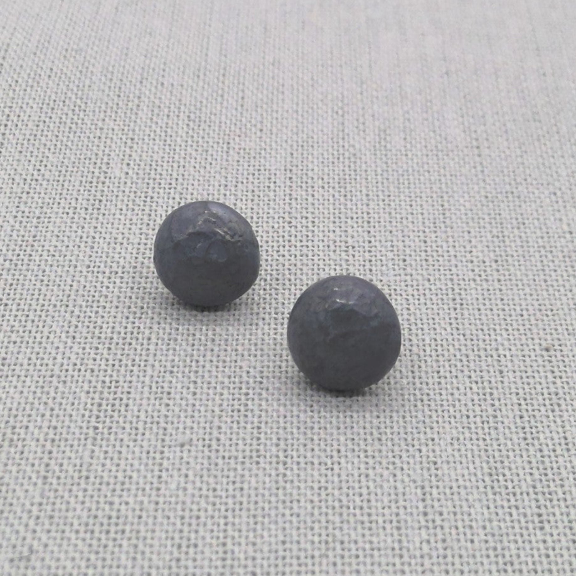 Oxidized black recycled silver ball stud earrings with hammered texture on fabric