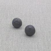 Close-up pair of black textured recycled silver stud earrings