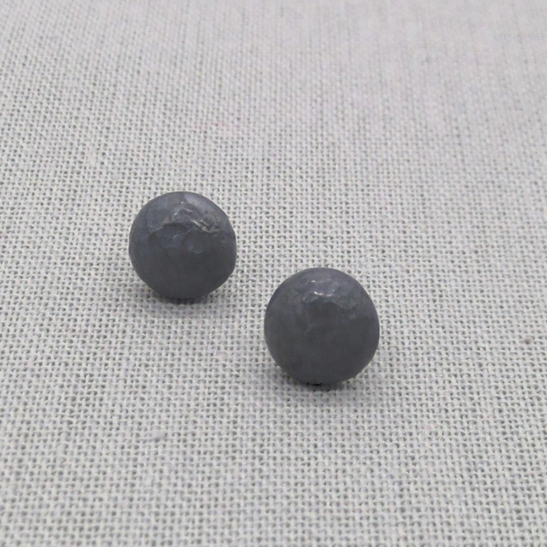 Close-up pair of black textured recycled silver stud earrings