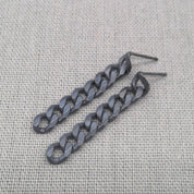 Angled view of black chain-link earrings made from recycled sterling silver