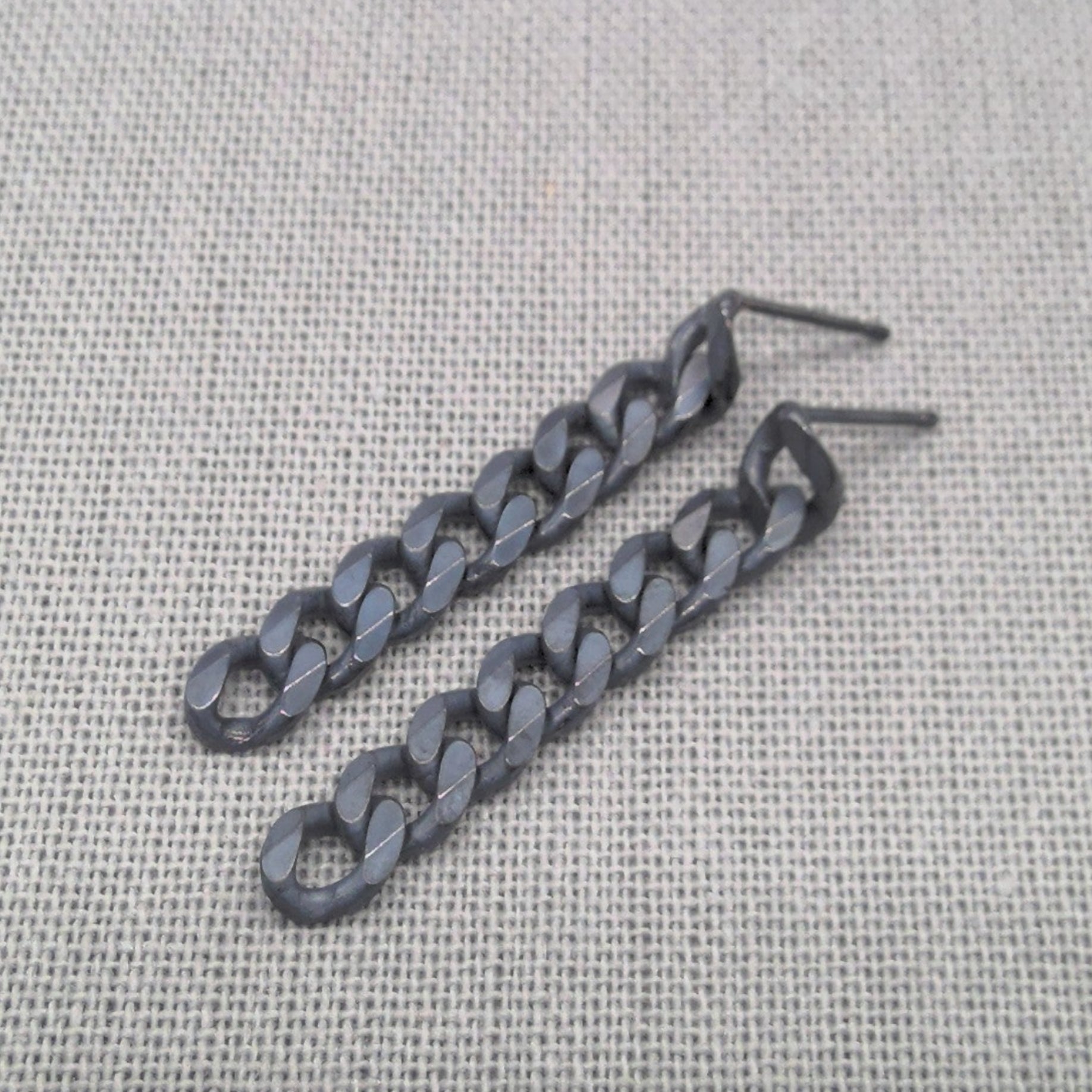 Angled view of black chain-link earrings made from recycled sterling silver