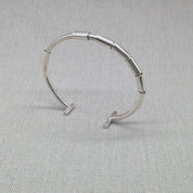 Angled view of open recycled silver bangle showing gap and clasp ends