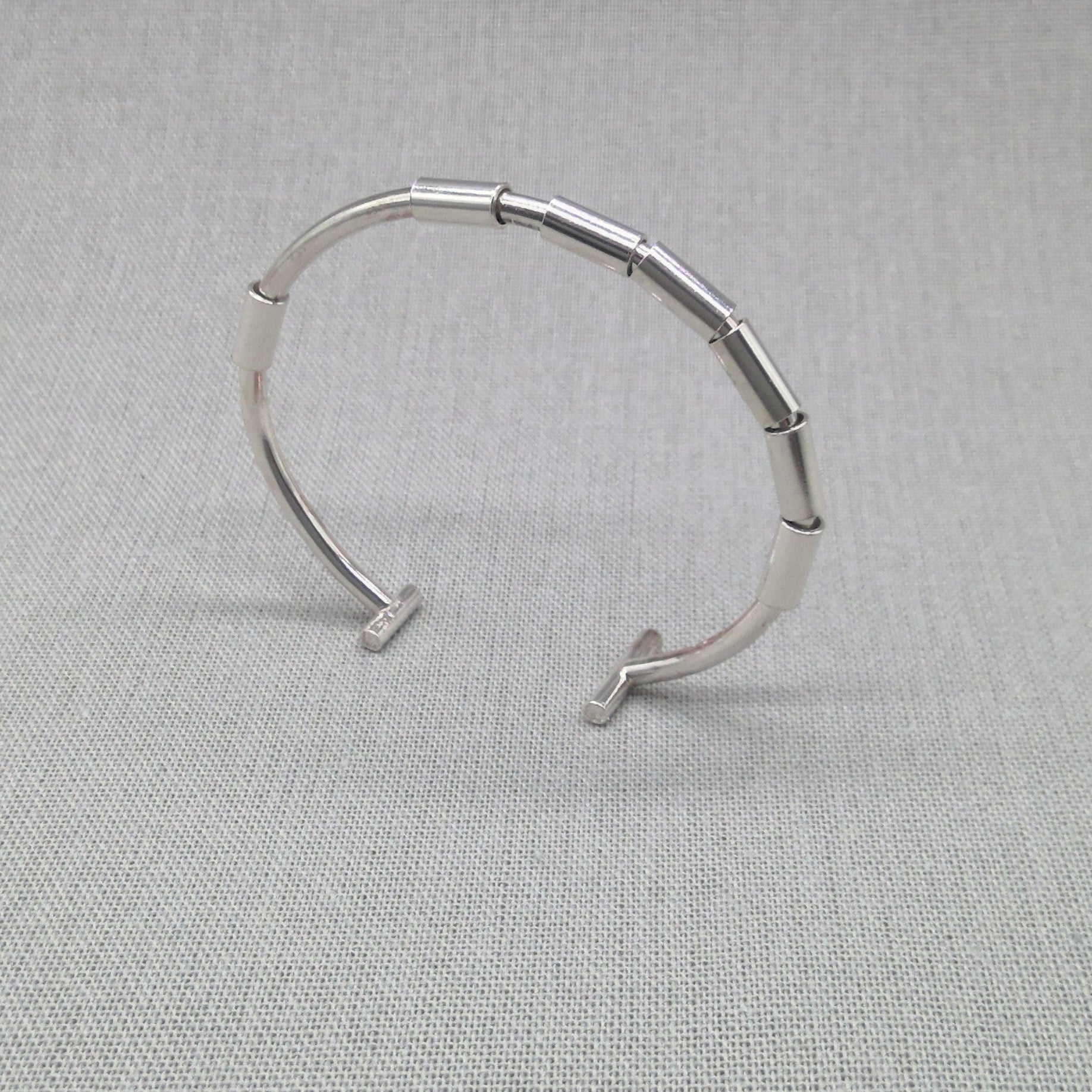 Angled view of open recycled silver bangle showing gap and clasp ends