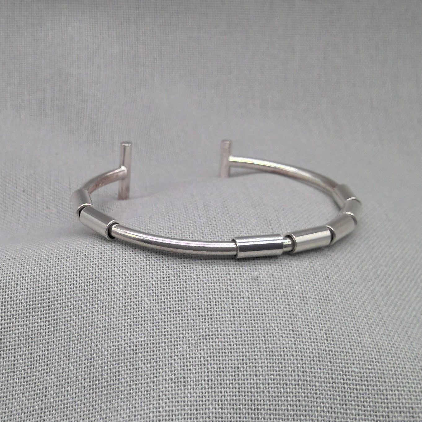 Side view of jointed segmented silver bangle with open design