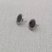 Angled view of black resin stud earrings in recycled silver