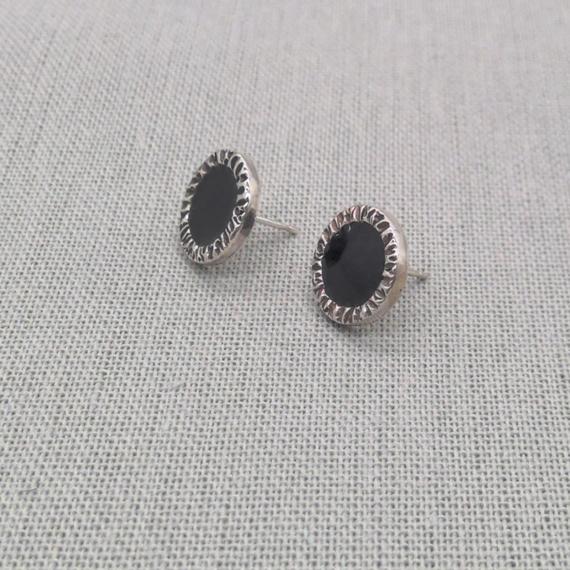 Angled view of black resin stud earrings in recycled silver