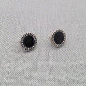 Close-up of black resin stud earring showing textured silver border