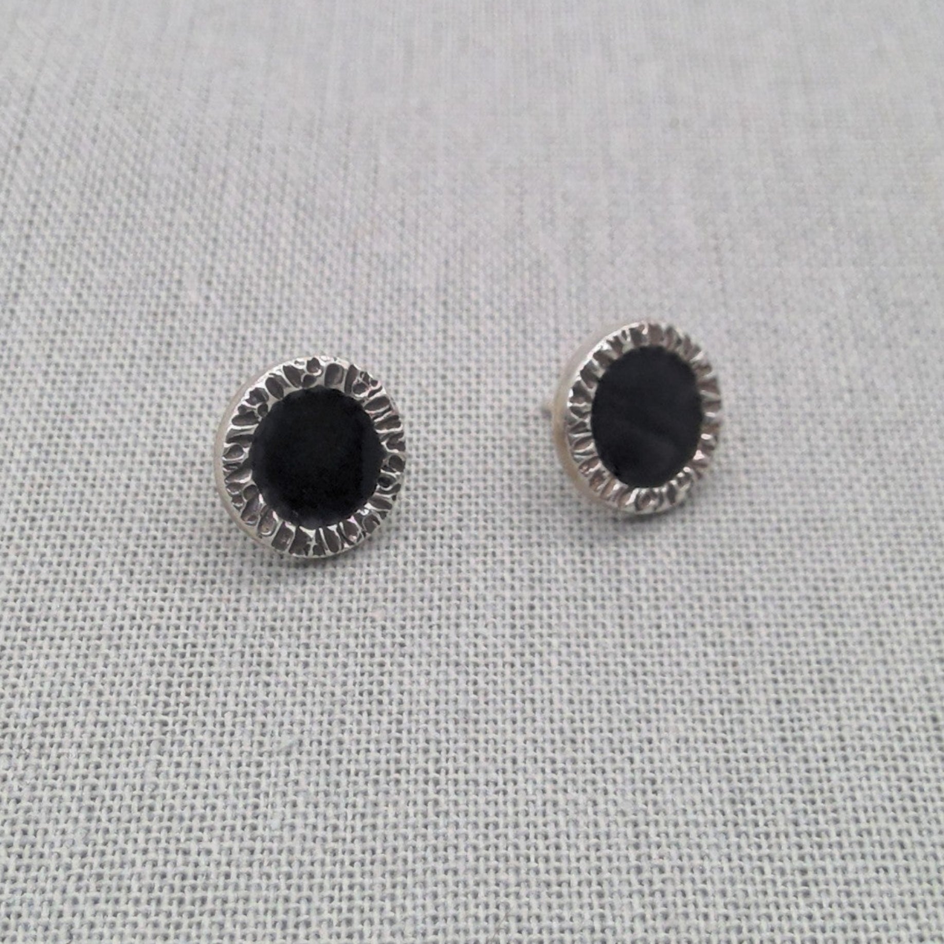 Close-up of black resin stud earring showing textured silver border