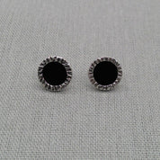 Pair of black resin stud earrings with textured silver edge