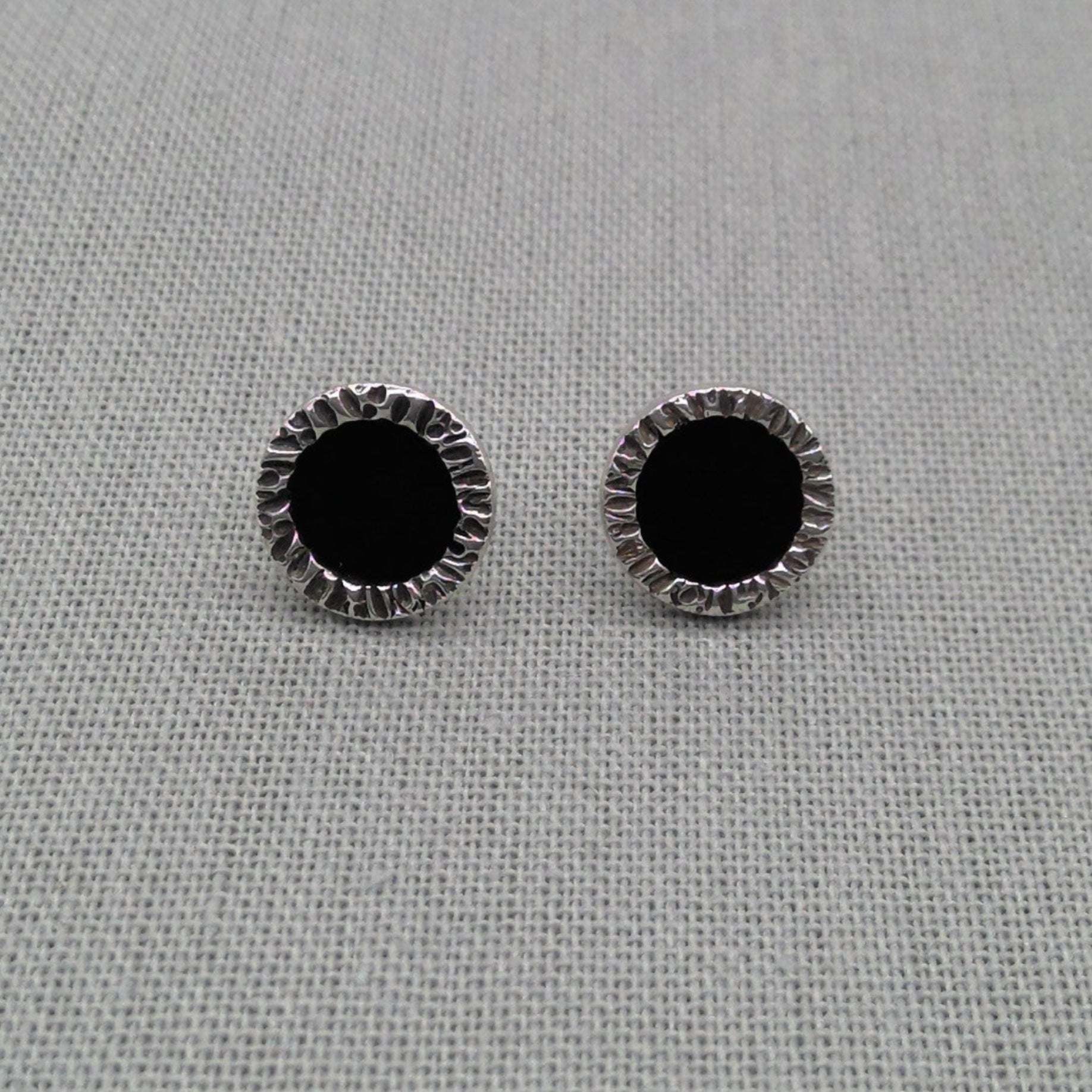 Pair of black resin stud earrings with textured silver edge