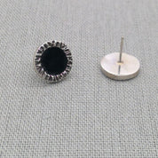 Side view of black resin stud earring showing post and backing