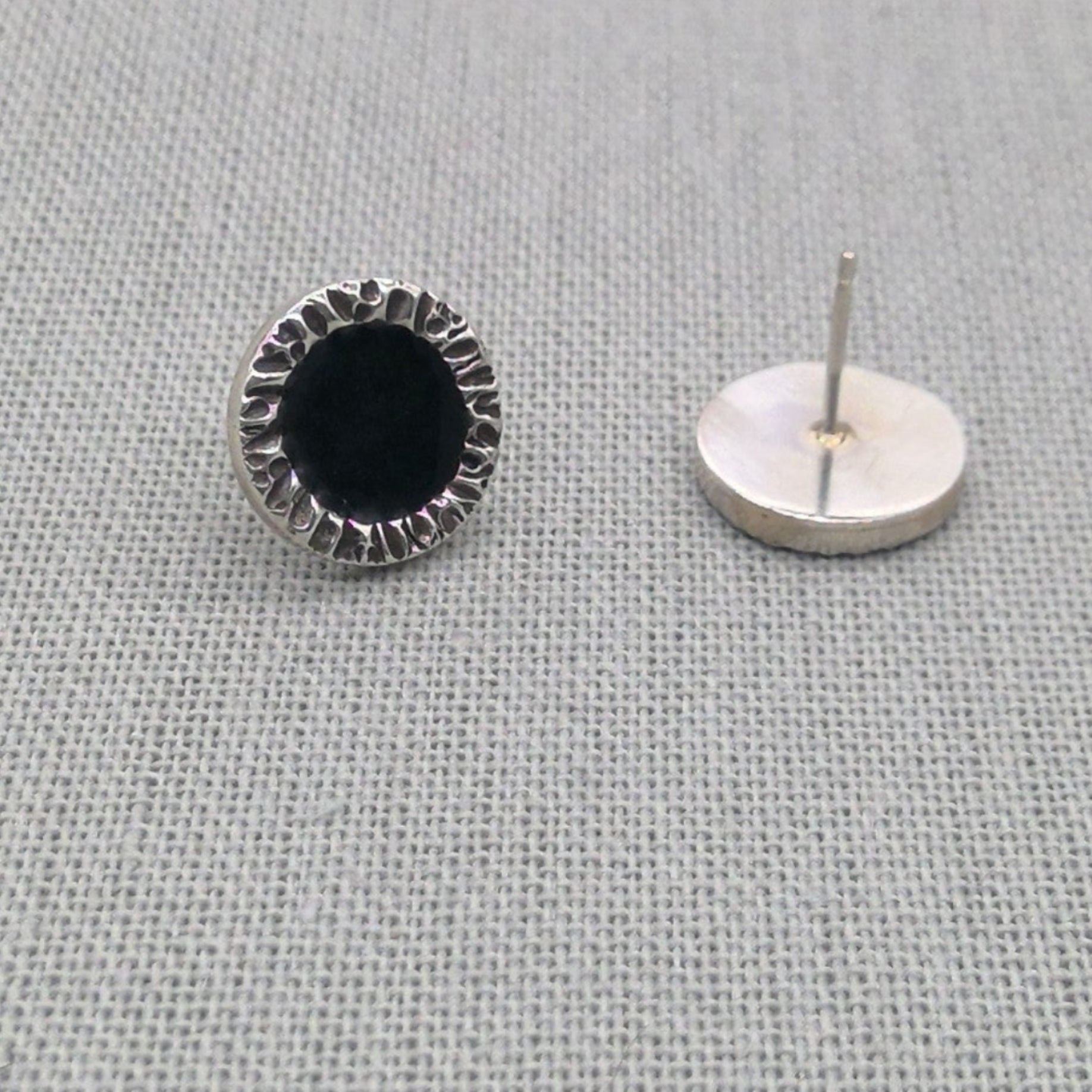 Side view of black resin stud earring showing post and backing