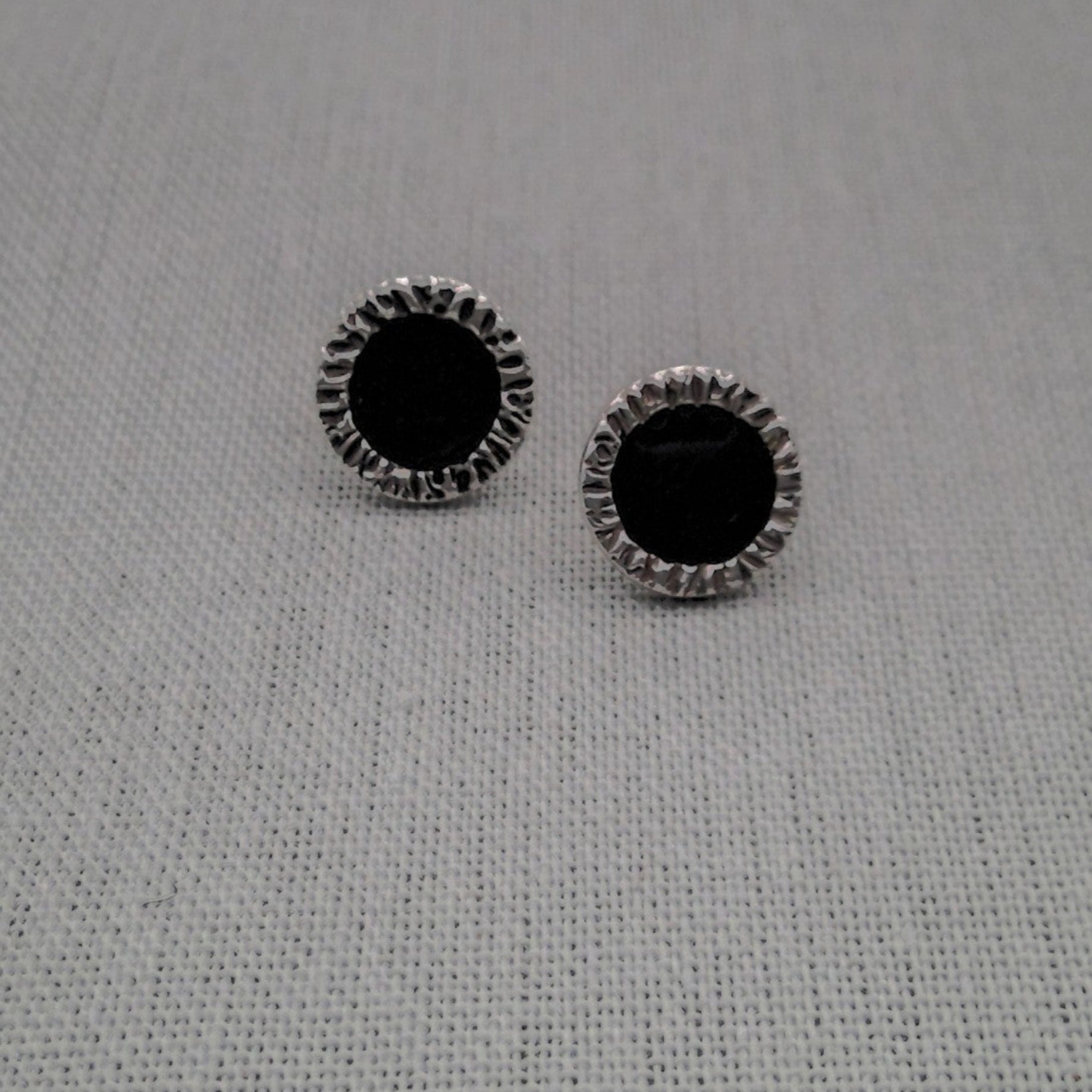Black and white resin stud earrings in recycled silver on fabric
