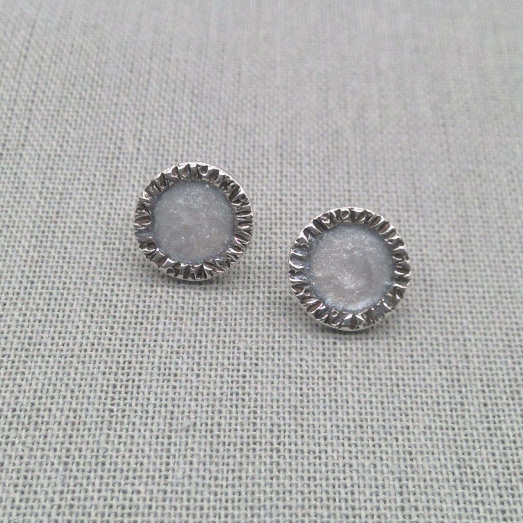 Pair of white resin stud earrings with textured silver edge