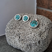 Set of earrings with turquoise stones on a textured stone surface