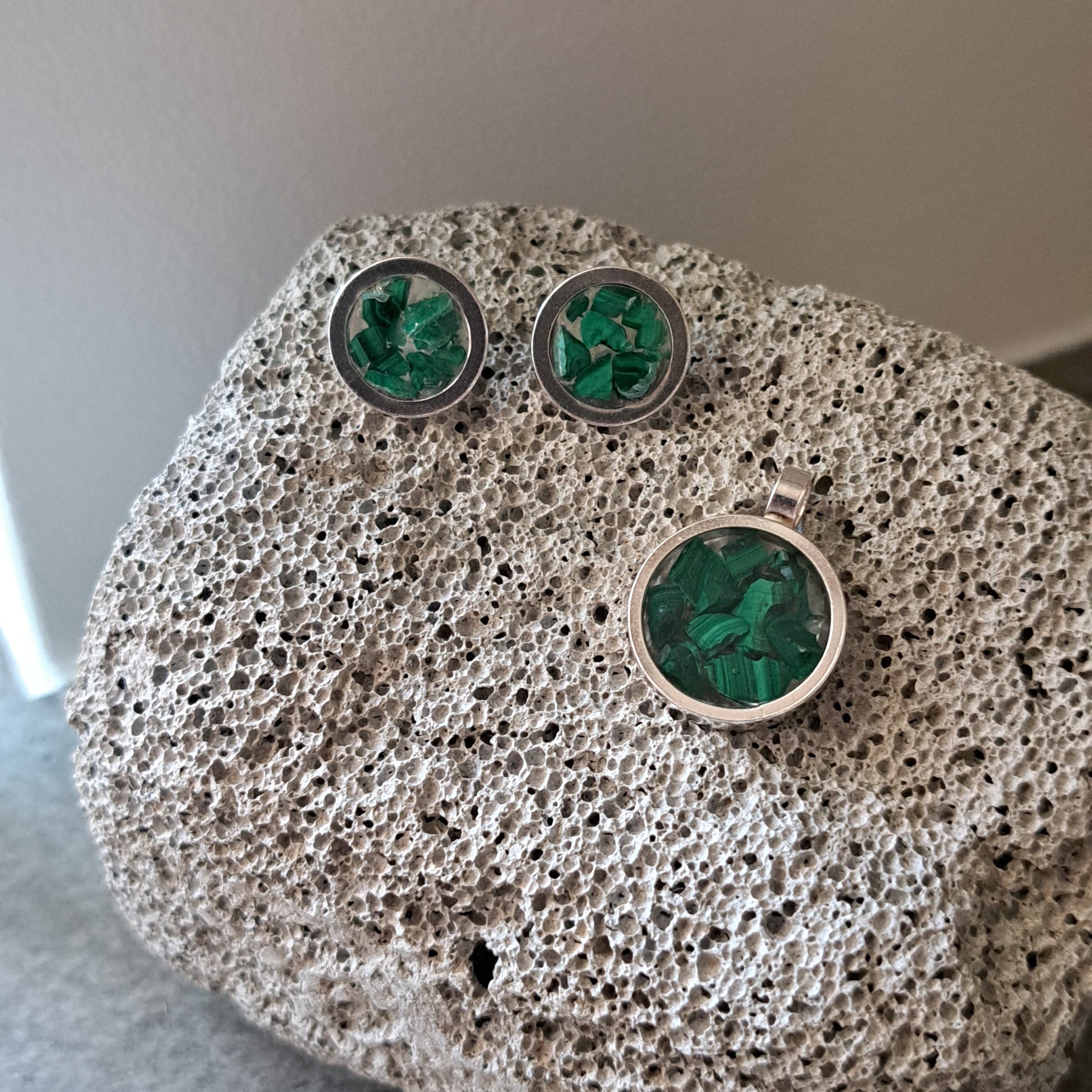 Jewelry with green gemstones on a textured stone surface