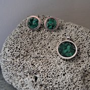 Three green gemstone rings on a textured stone surface