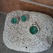 Set of earrings with green gemstones on a textured stone surface