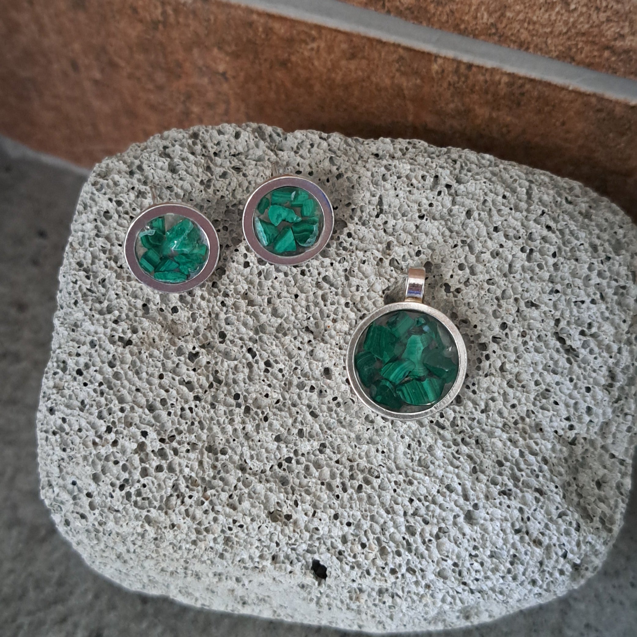 Set of earrings with green gemstones on a textured stone surface