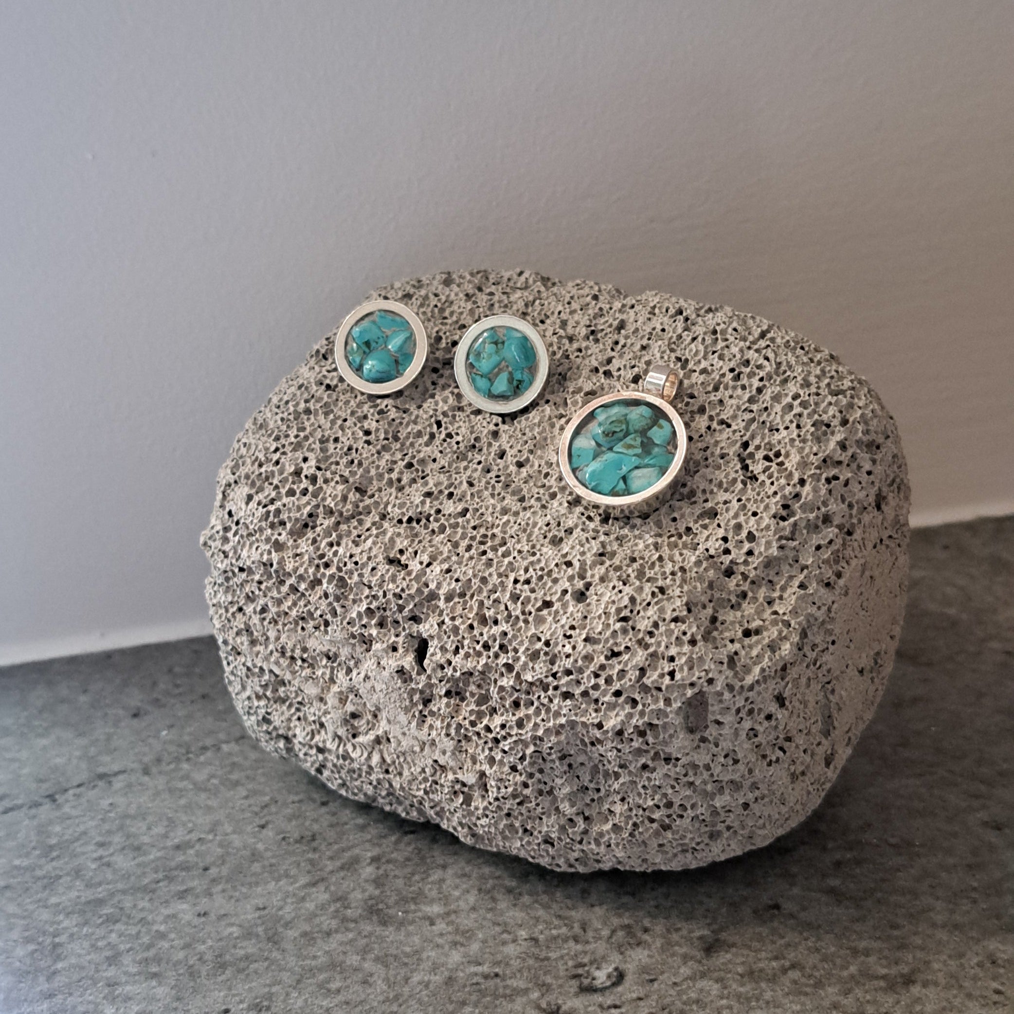 Decorative stone with embedded green stones on a plain background