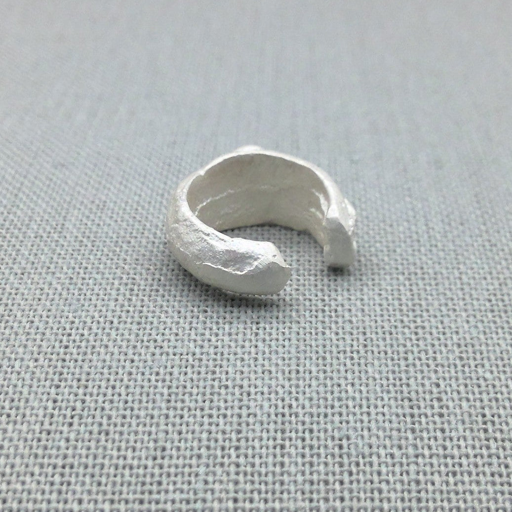 Sculptural recycled silver ear cuff with organic texture on fabric