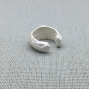 Sculptural recycled silver ear cuff with organic texture on fabric