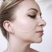 Model wearing sculptural recycled silver face chain draped across cheek