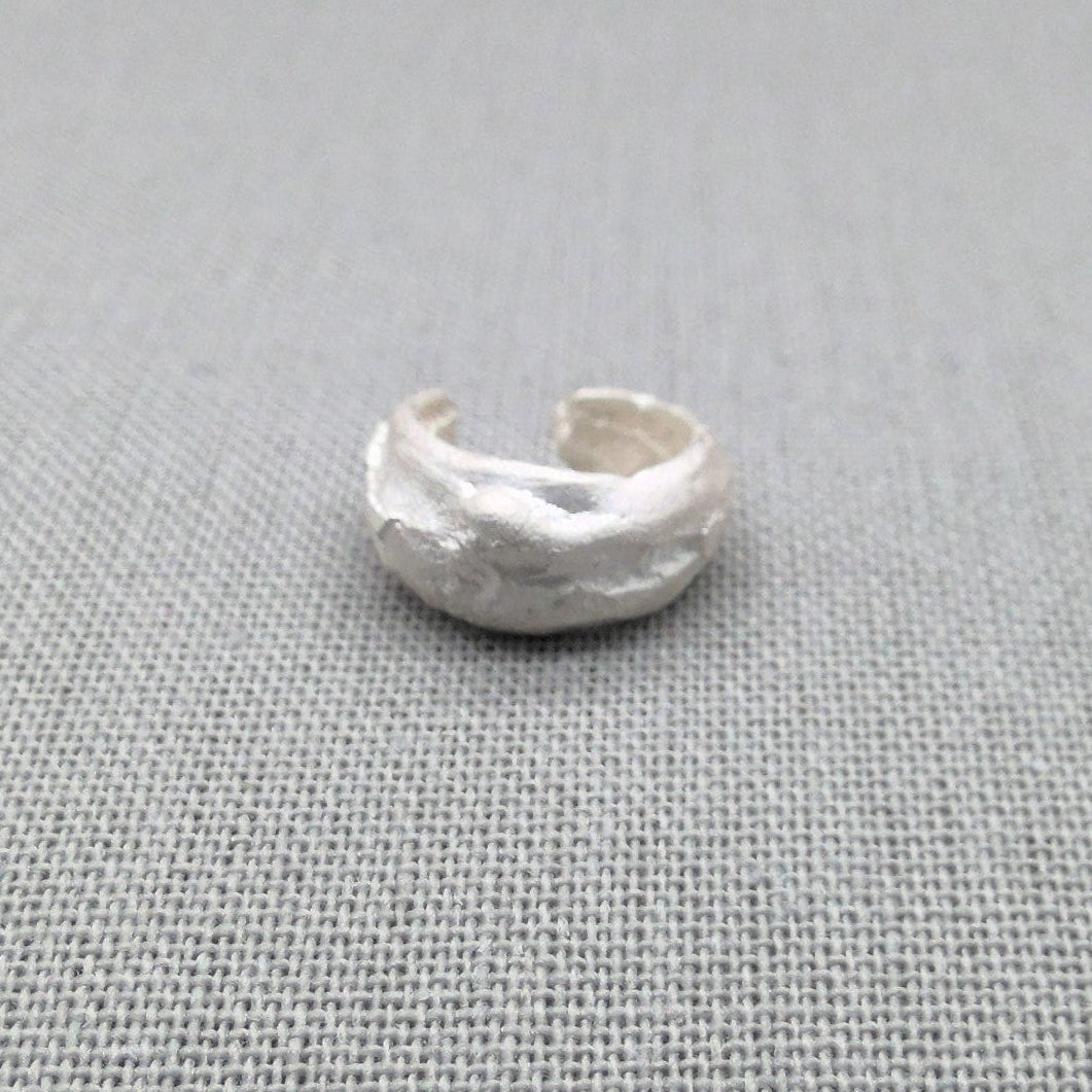 Angled view of recycled silver ear cuff with organic surface