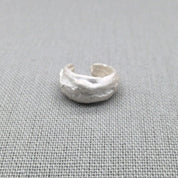 Angled view of recycled silver ear cuff with organic surface