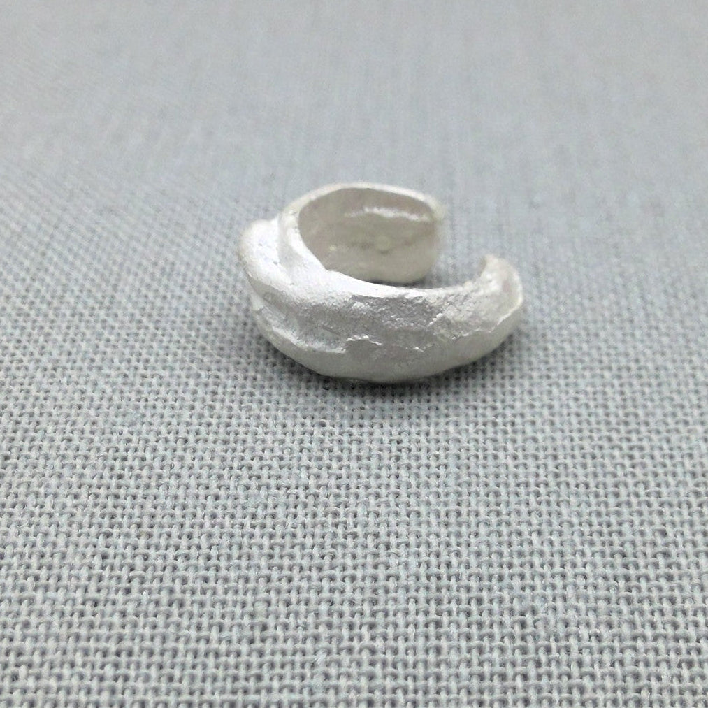 Close-up of textured molten surface on sculptural silver ear cuff