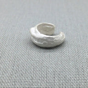 Close-up of textured molten surface on sculptural silver ear cuff