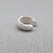 Side view of sculptural silver ear cuff showing molten texture