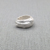 Top-down view of sculptural silver ear cuff showing open design