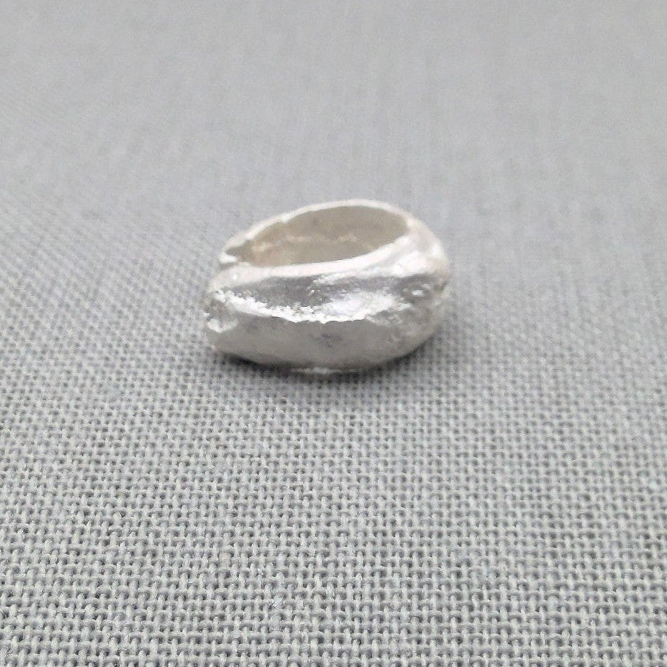 Top-down view of sculptural silver ear cuff showing open design