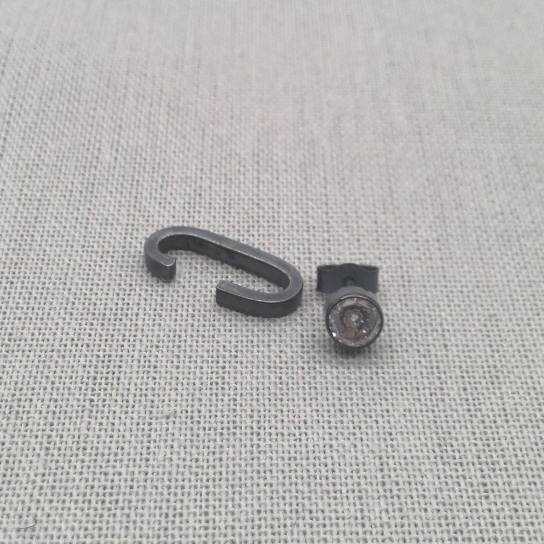Close-up of black recycled silver cuff and zircon stud earrings